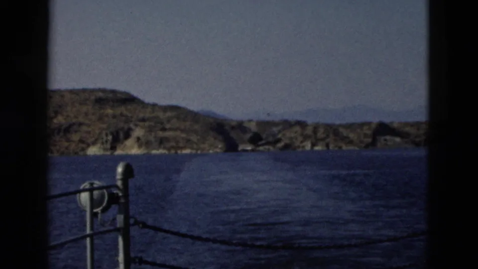 1958 Yellowstone boat view with metal railing, deep blue lake water, and rocky shore rising in the distance.