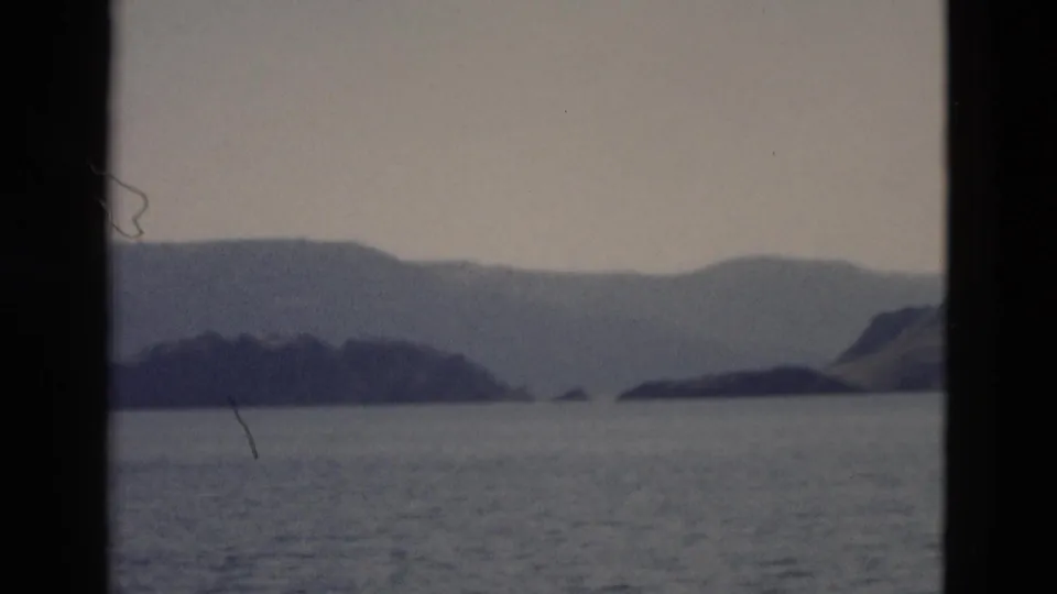 Yellowstone home-movie footage from 1958 frames a broad lake, small islands, and rolling mountain shoreline.