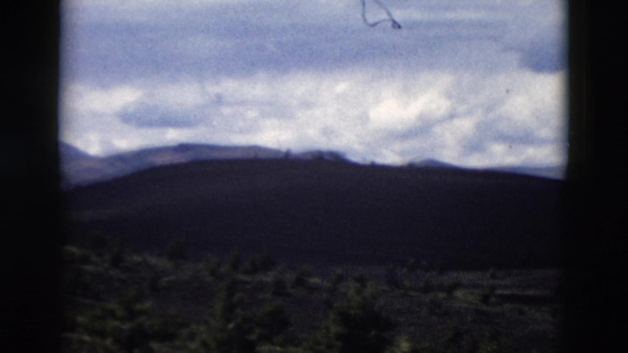 Yellowstone landscape frame with shadowed hills, distant ridges, soft clouds, and visible 8mm gate edges.
