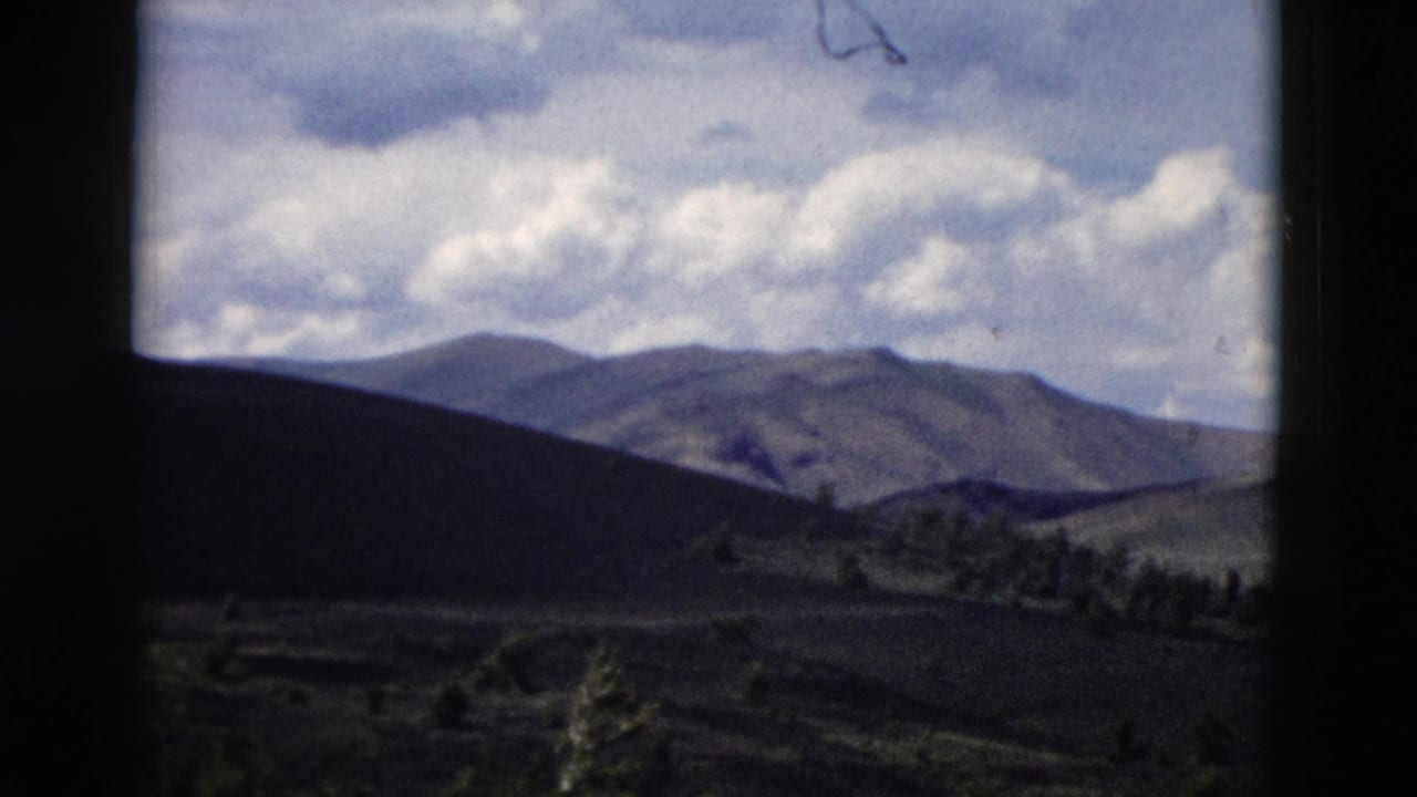 Distant mountain ridges under a cloudy blue sky with dark foreground hills.