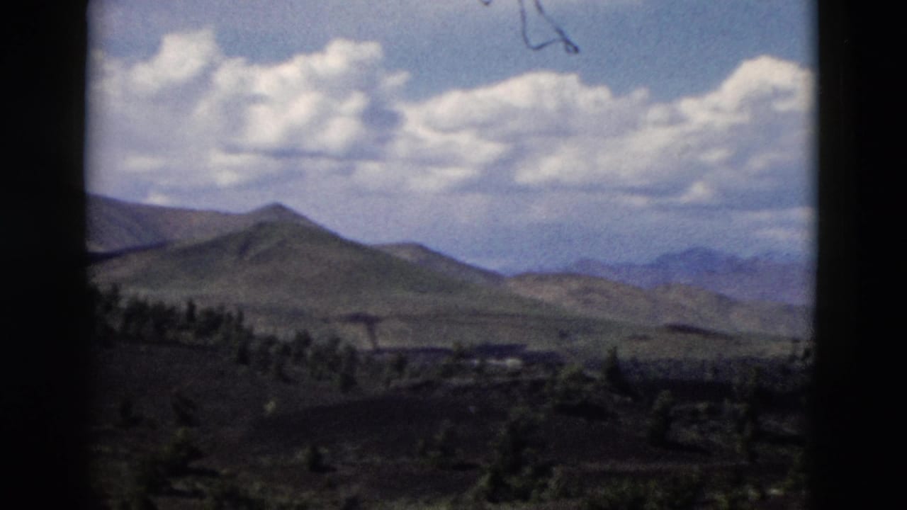 Distant mountain ridges and rolling hills beneath a clouded blue sky.