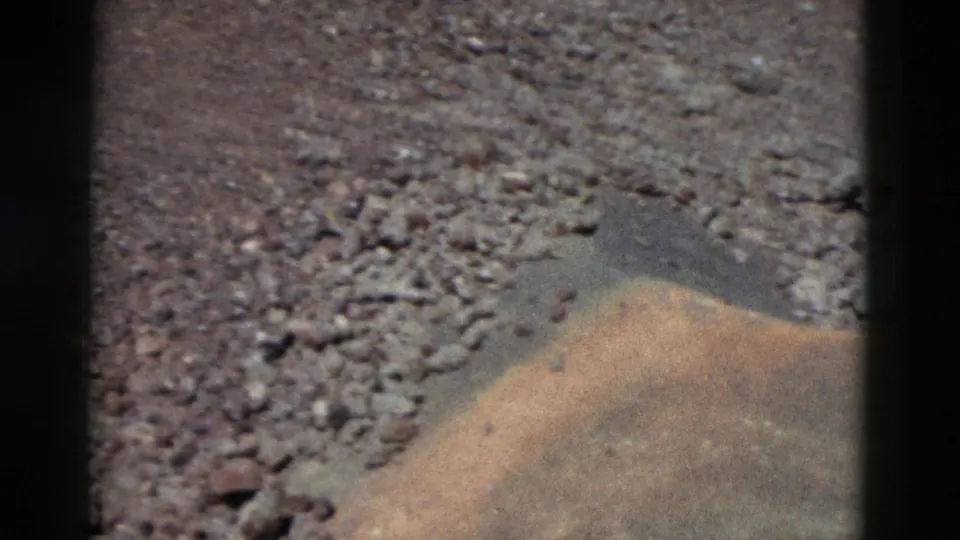 1958 Yellowstone 8mm frame showing gravelly soil and a low rounded mound near the bottom edge.