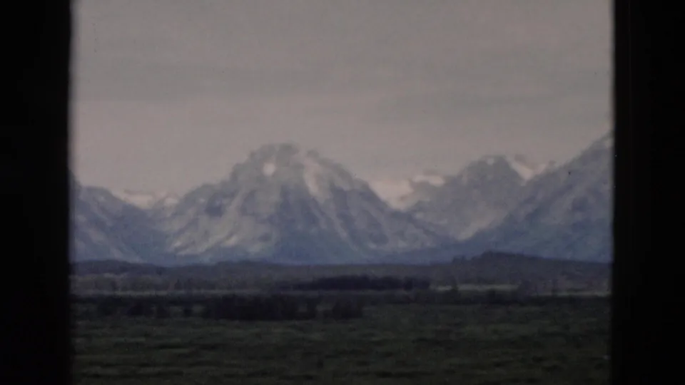 Snow-capped peaks and foothills appear in a soft 1958 8mm scenic view from the Yellowstone, Wyoming area.