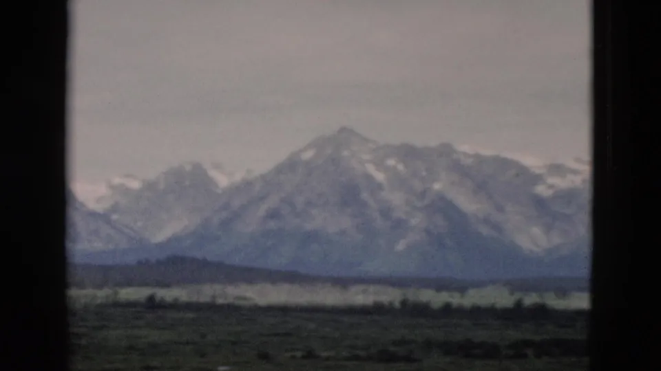 1958 Yellowstone-area 8mm frame of a broad mountain range beyond a dark green valley.