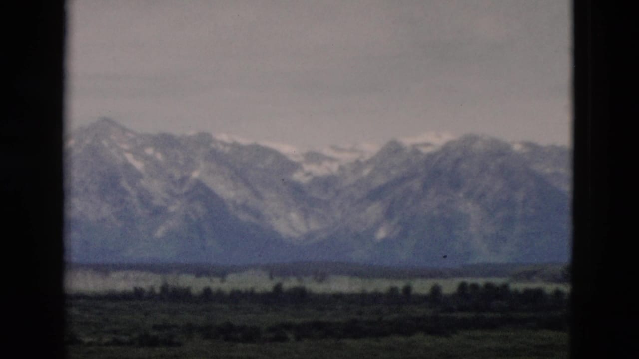 Distant mountain peaks and valley floor seen between dark vertical borders.