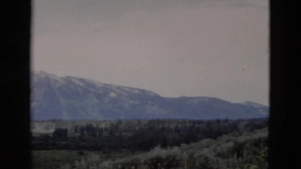 Yellowstone-area mountain landscape on 8mm film, with a broad valley and dark vertical framing from the shooting position.