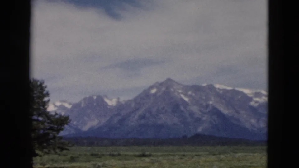 1958 8mm Yellowstone landscape frame showing a snow-dusted mountain range over open grassland.