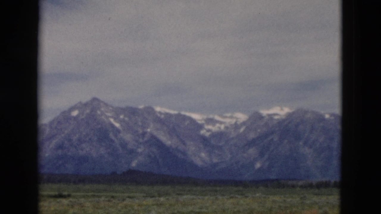 Snow-capped mountain range beyond open plains under a cloudy sky.