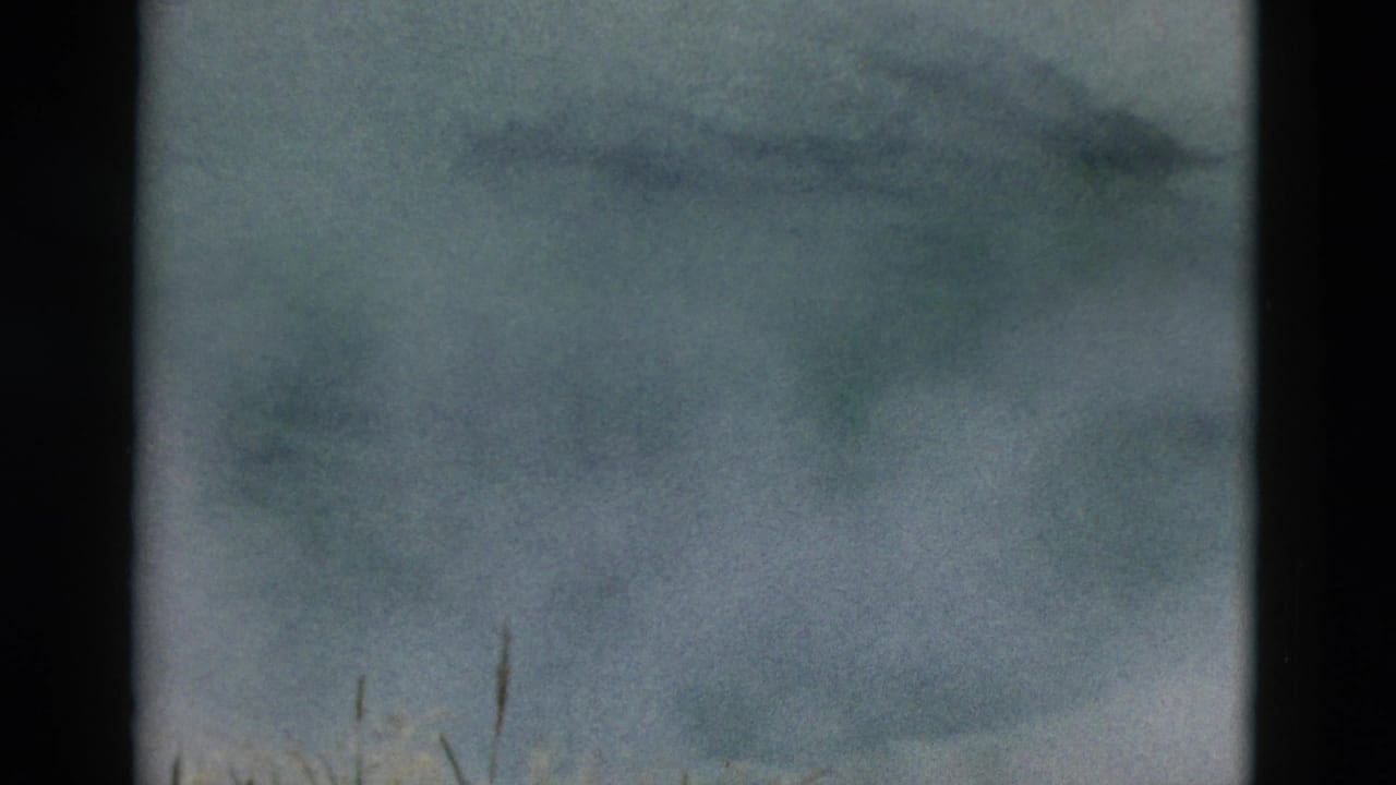 Yellowstone geothermal pond with light steam over ice and snow-toned water, recorded in soft 1950s 8mm color.