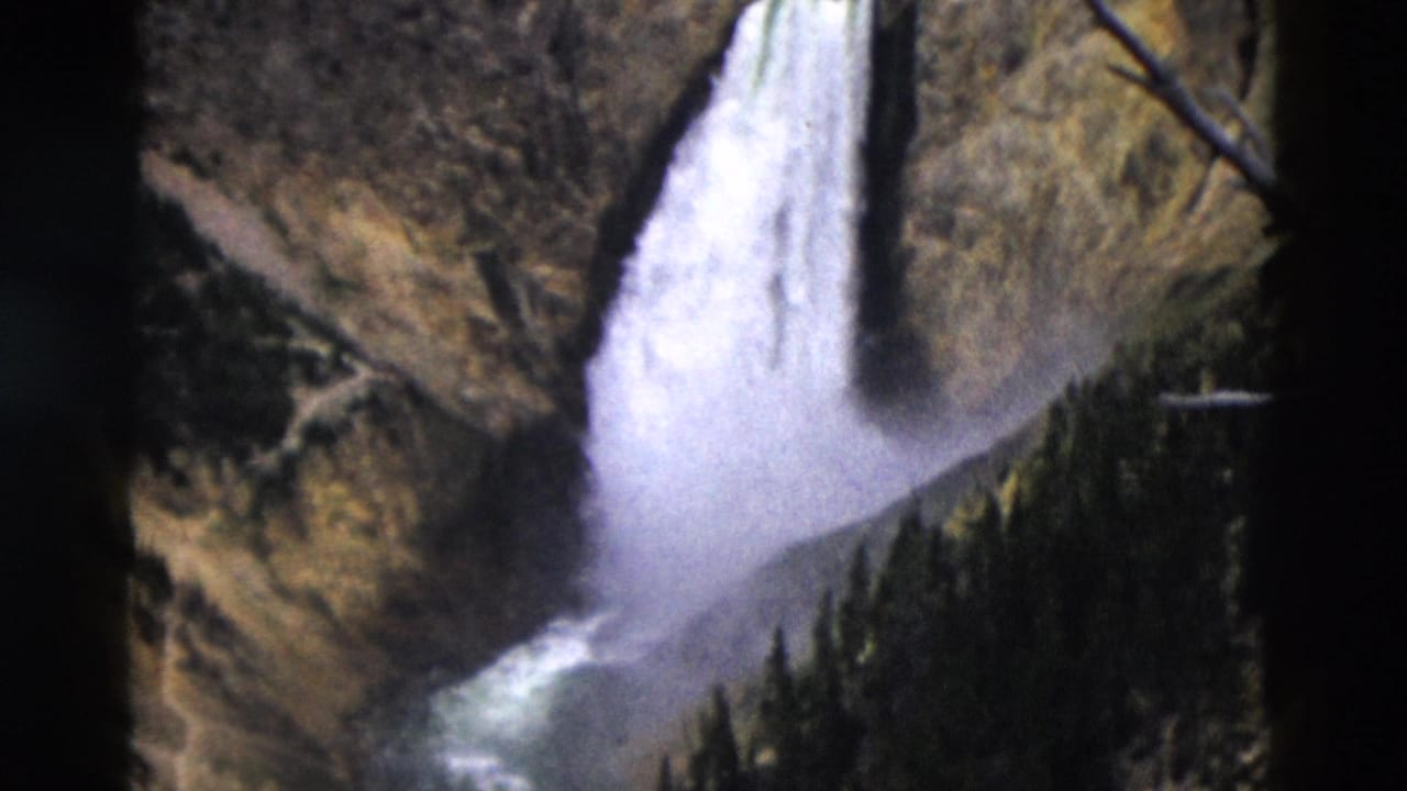 Closer view of a white waterfall spilling over a cliff into a rocky gorge.