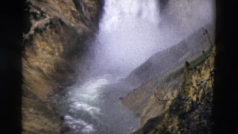 Yellowstone 8mm frame from 1958 showing waterfall spray, a river channel, and rugged canyon walls below the falls.