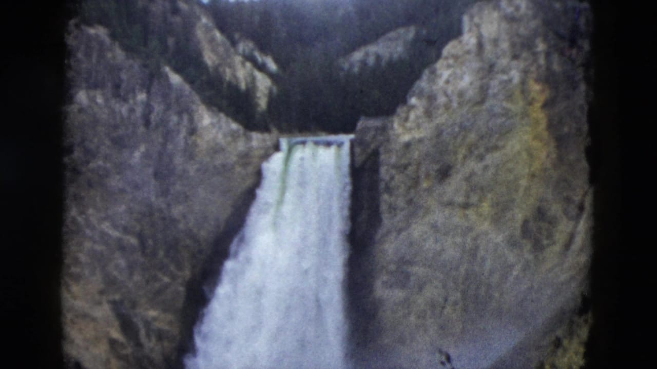 Waterfall dropping between steep rocky canyon walls.