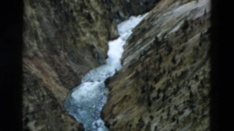 1958 Yellowstone home-movie frame showing white water cutting through steep, layered canyon walls.