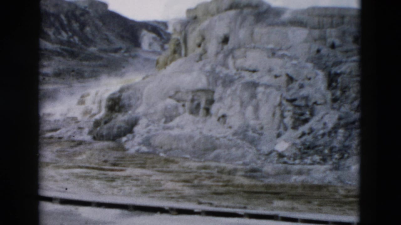 Pale terraced rock formations with wet foreground and dark slopes behind.