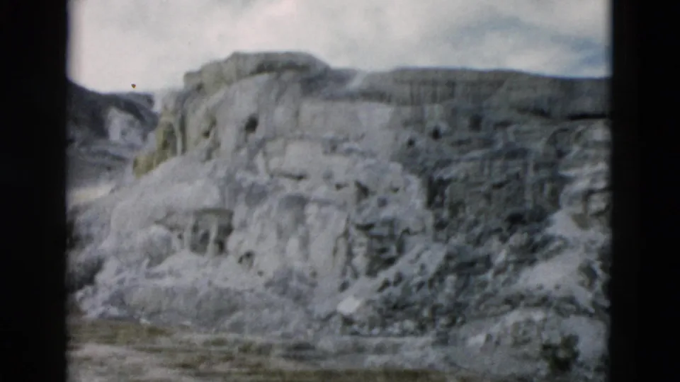 1958 Yellowstone frame with pale mineral terraces filling the view and darker rugged terrain along the right edge.