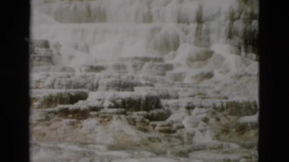 1958 8mm Yellowstone footage showing pale mineral terraces and stepped rock formations in a soft, grainy frame.