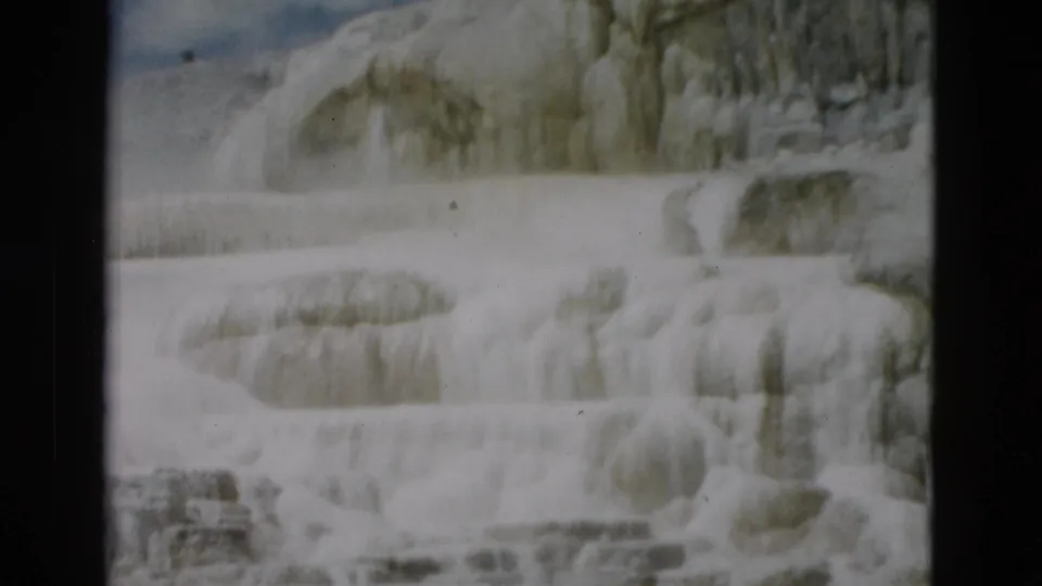 1958 8mm Yellowstone view of rounded mineral terrace forms with muted color and home-movie grain.