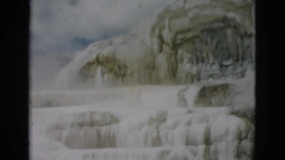 1958 Yellowstone 8mm frame showing pale terraced rock formations below a small area of blue sky.