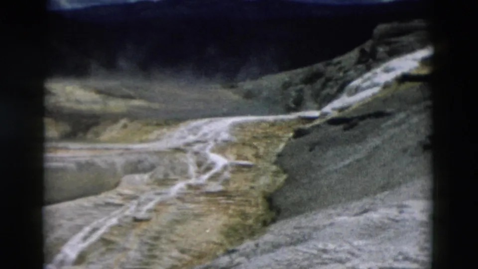 1958 Yellowstone 8mm frame showing mineral runnels, rocky slopes, and soft-edged terrace formations in the geothermal area.