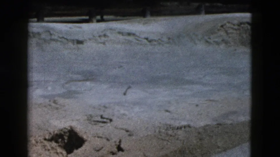 Close view of pale roadside ground in the 1958 Yellowstone 8mm clip, with grain, soft focus, and film-frame borders.