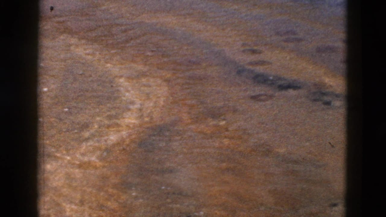 High-angle view of dry brown land with dark vertical bars at the sides.