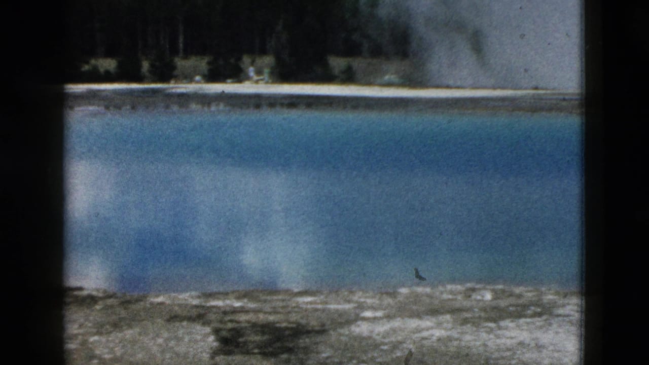1958 Yellowstone frame with blue geothermal water, soft steam plumes, mineral-streaked foreground, and a wooded background.
