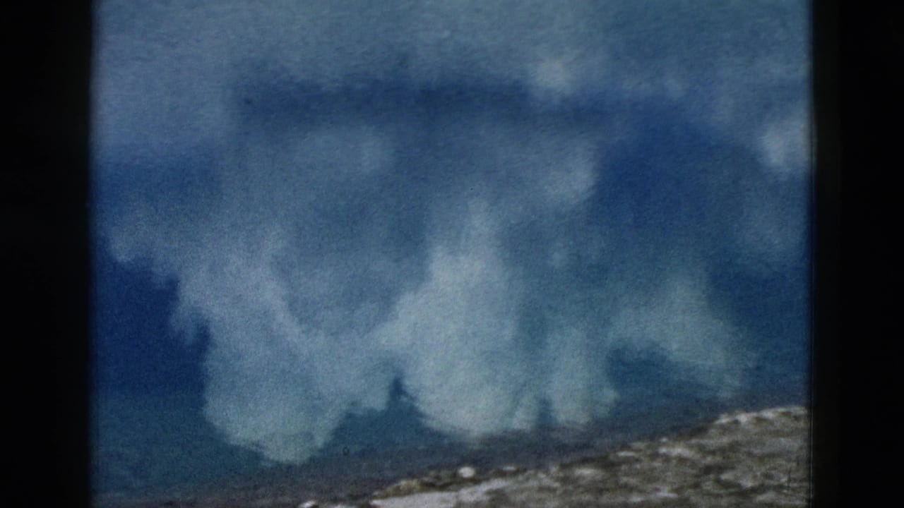 Yellowstone lake reflection frame with soft white clouds mirrored in blue water and a narrow shoreline strip.
