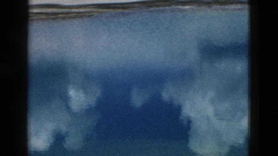 Yellowstone lake frame showing blue water, cloud reflections, and a thin shoreline, with the view held steady.
