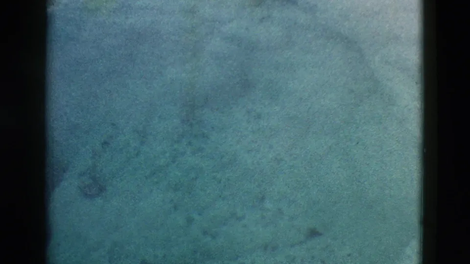 Final 1958 Yellowstone 8mm frame with blue-gray haze, faint smoke texture, and indistinct natural terrain.