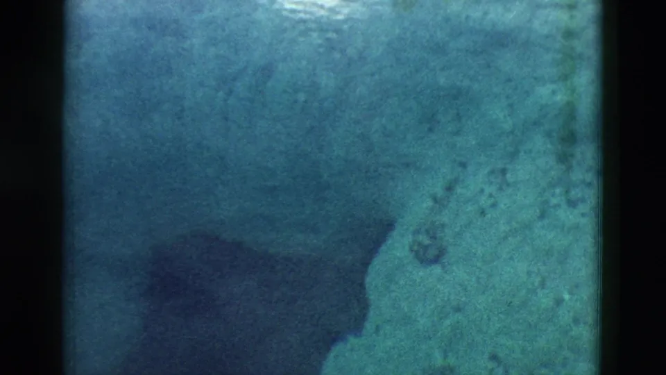 1958 Yellowstone 8mm view of a deep spring with pale mineral or rock surfaces and shadowed underwater shapes.