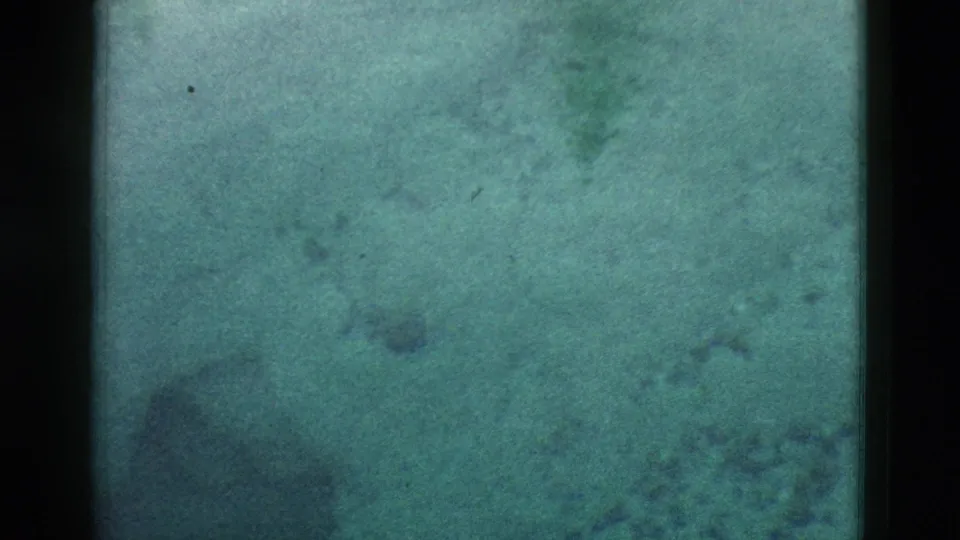 1958 8mm Yellowstone footage begins with a soft, green-blue exposed frame and dark gate edges, with faint geothermal forms barely visible.