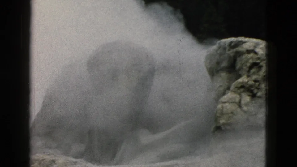 Dense Yellowstone geothermal steam drifts across rough rock, partly obscuring the vent area in grainy 1958 8mm footage.
