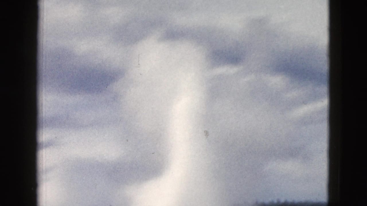 Old Faithful geyser plume rising behind dark vertical framing bars.