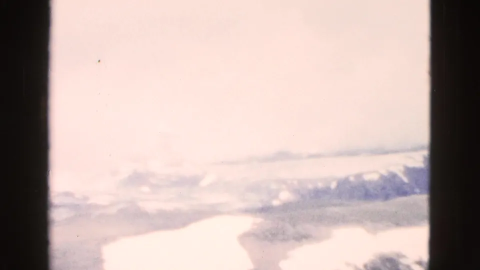 1958 Yellowstone home-movie frame with bright snow, pale overcast sky, and a distant ridge, partly washed by 8mm exposure bloom.