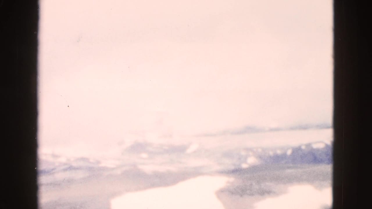 Hazy pale sky above faint distant mountains and a light-toned valley edge.