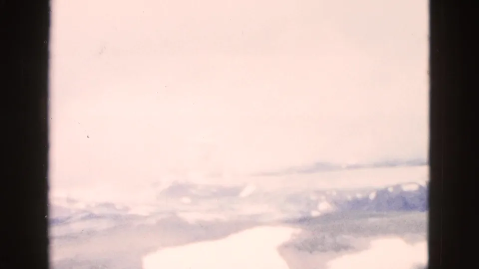 1958 Yellowstone-area 8mm frame with hazy sky, faint ridgelines, and a washed, overexposed valley view at the start of the pan.