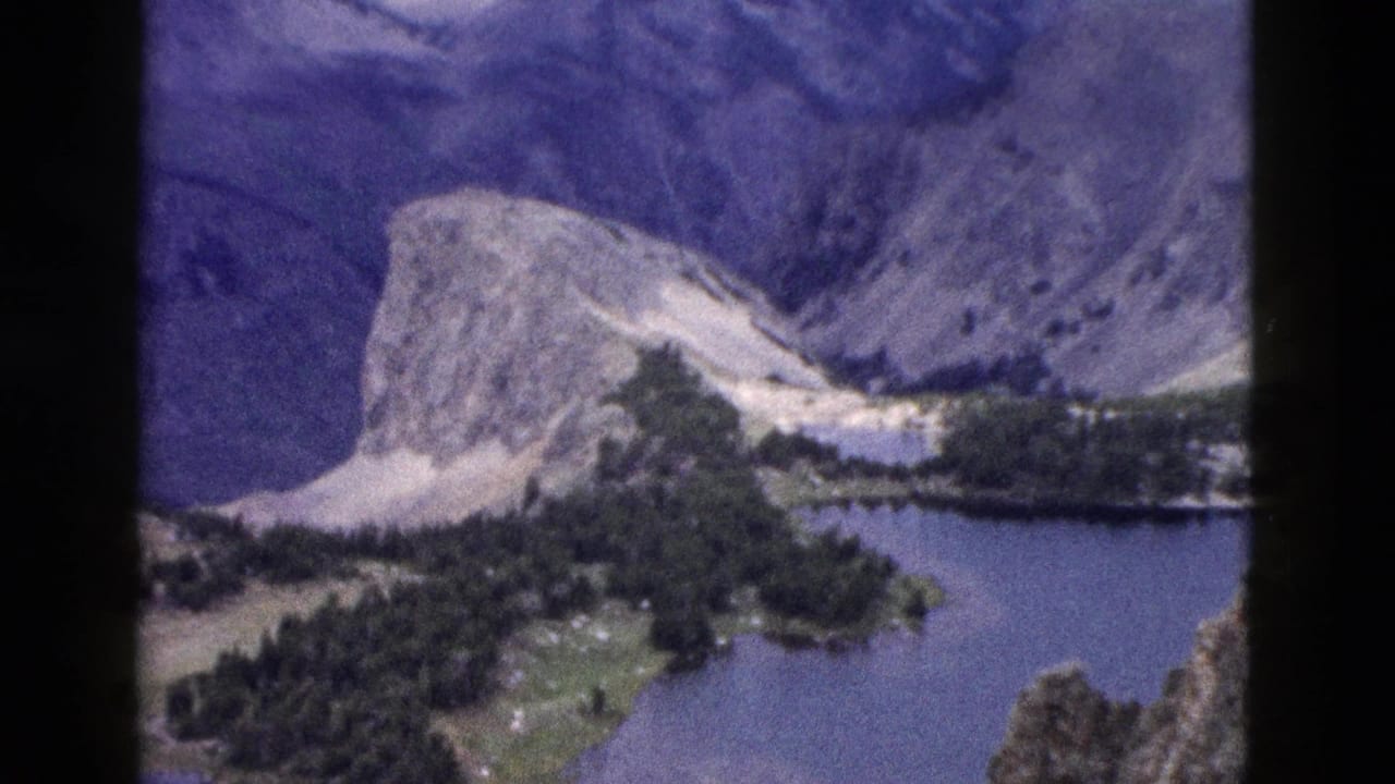 Distant rocky mountain above a blue lake and evergreen forest.