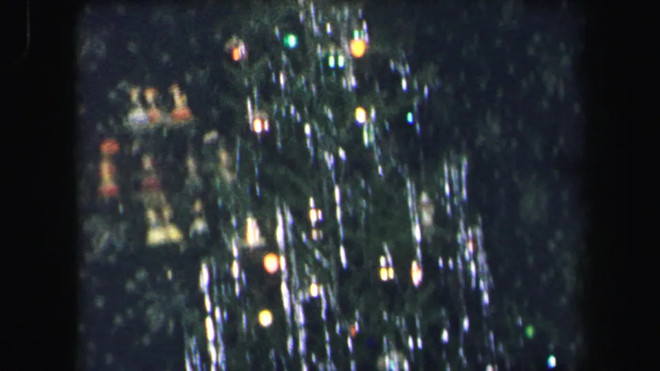 1971 8mm home-movie frame from Lynbrook showing a Christmas tree with colored lights and shimmering tinsel.