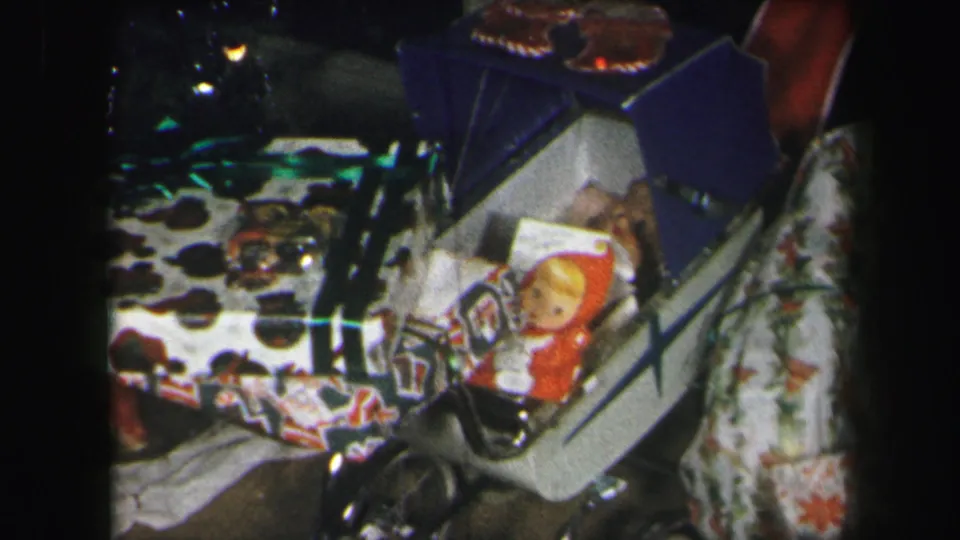 1971 Lynbrook frame with holiday presents, a red-hooded doll or toy figure, patterned wrapping paper, and nearby household textiles.