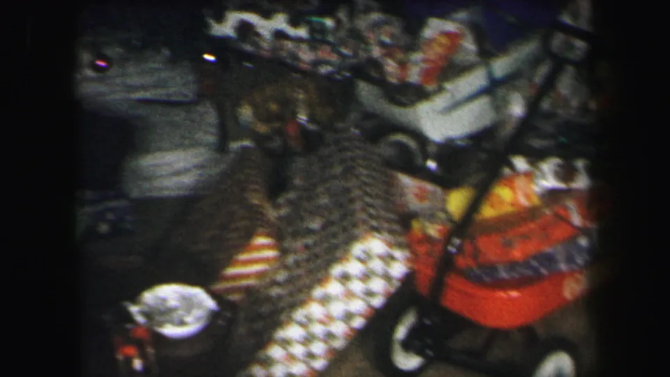 Soft 8mm frame from the Lynbrook Christmas scene showing the gift-filled wagon, patterned fabric, toys, and stroller handle.