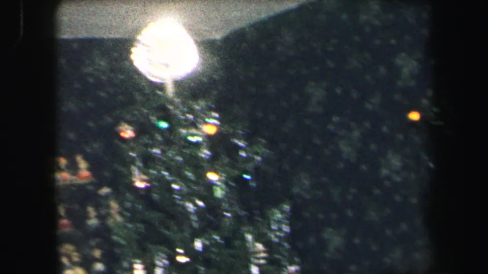 1971 Lynbrook home-movie view of a bright Christmas tree topper above tinsel, ornaments, and colored lights.