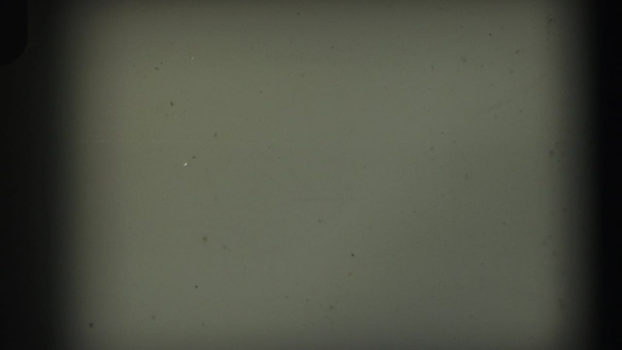 Blank or leader-like 8mm frame from the supplied 1971 Lynbrook home movie, with dust, scratches, and dark gate edges visible.
