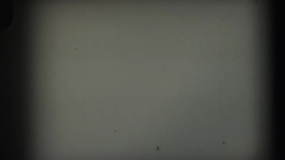 Mostly blank 8mm frame from the supplied 1971 Lynbrook home movie, showing film grain, dust, scratches, and uneven exposure.
