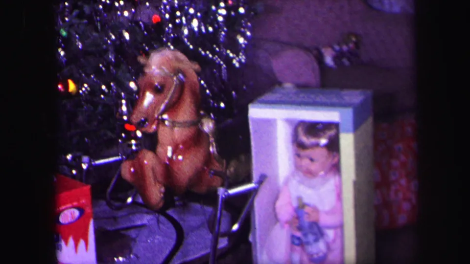 1971 Lynbrook frame showing a toy rocking horse, a boxed doll, and wrapped gifts beside a tinsel-covered Christmas tree.