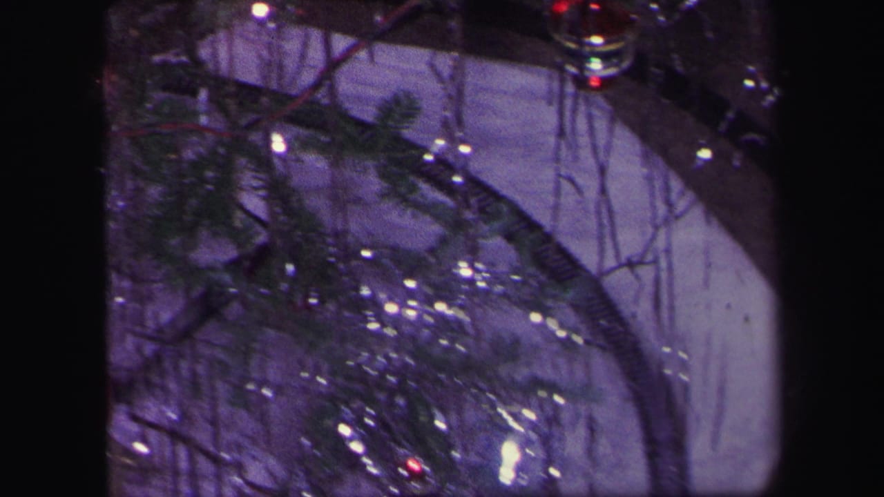 Tinsel-covered Christmas tree branches with small ornaments and a curved train track.