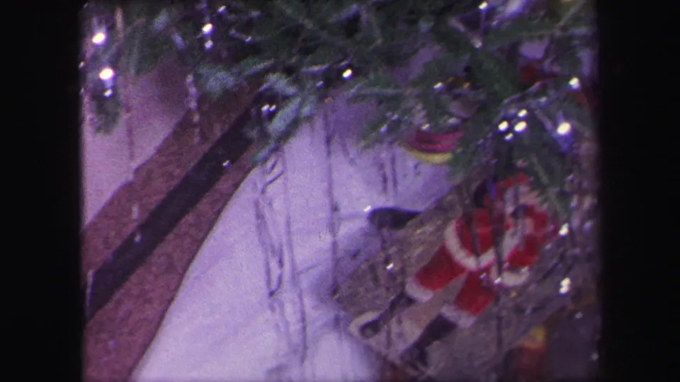 1971 Lynbrook frame showing the train track under the Christmas tree, with tinsel, ornaments, and a small Santa figure near the base.