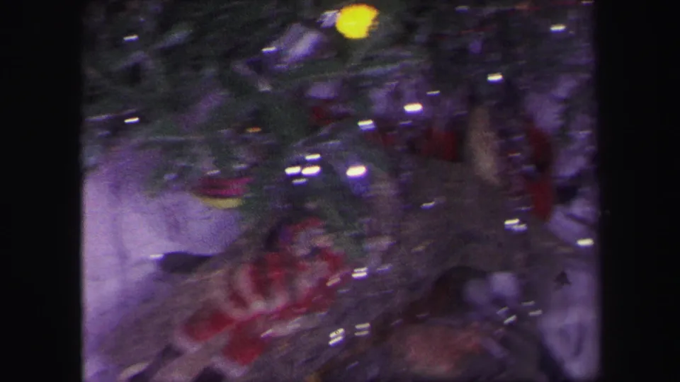 Soft 8mm frame from Lynbrook in 1971 showing tinsel, ornaments, and a partially obscured Santa figure near the toy train setup.