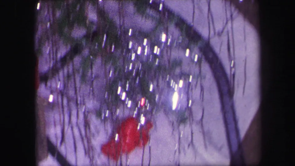 1971 Lynbrook home-movie frame with sparkling tinsel, tree branches, white display base, and a red Santa-like figure near the train scene.