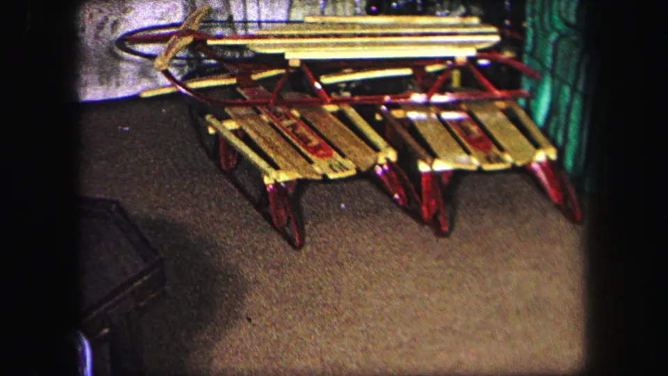 Three wooden sleds with red runners are arranged near a decorated Christmas tree and train track in Lynbrook, New York, 1971.