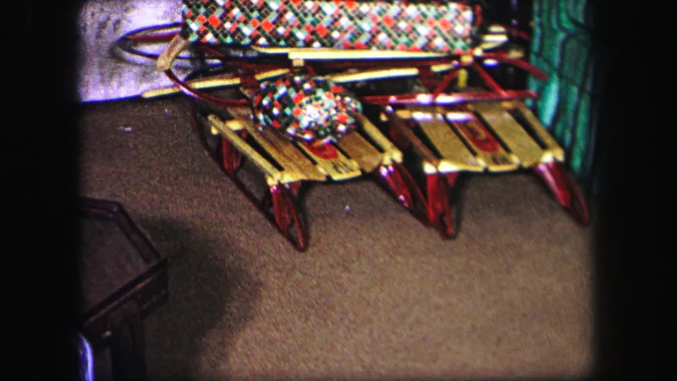 1971 Lynbrook Christmas frame showing a small wrapped gift placed on a wooden sled beneath a plaid blanket.